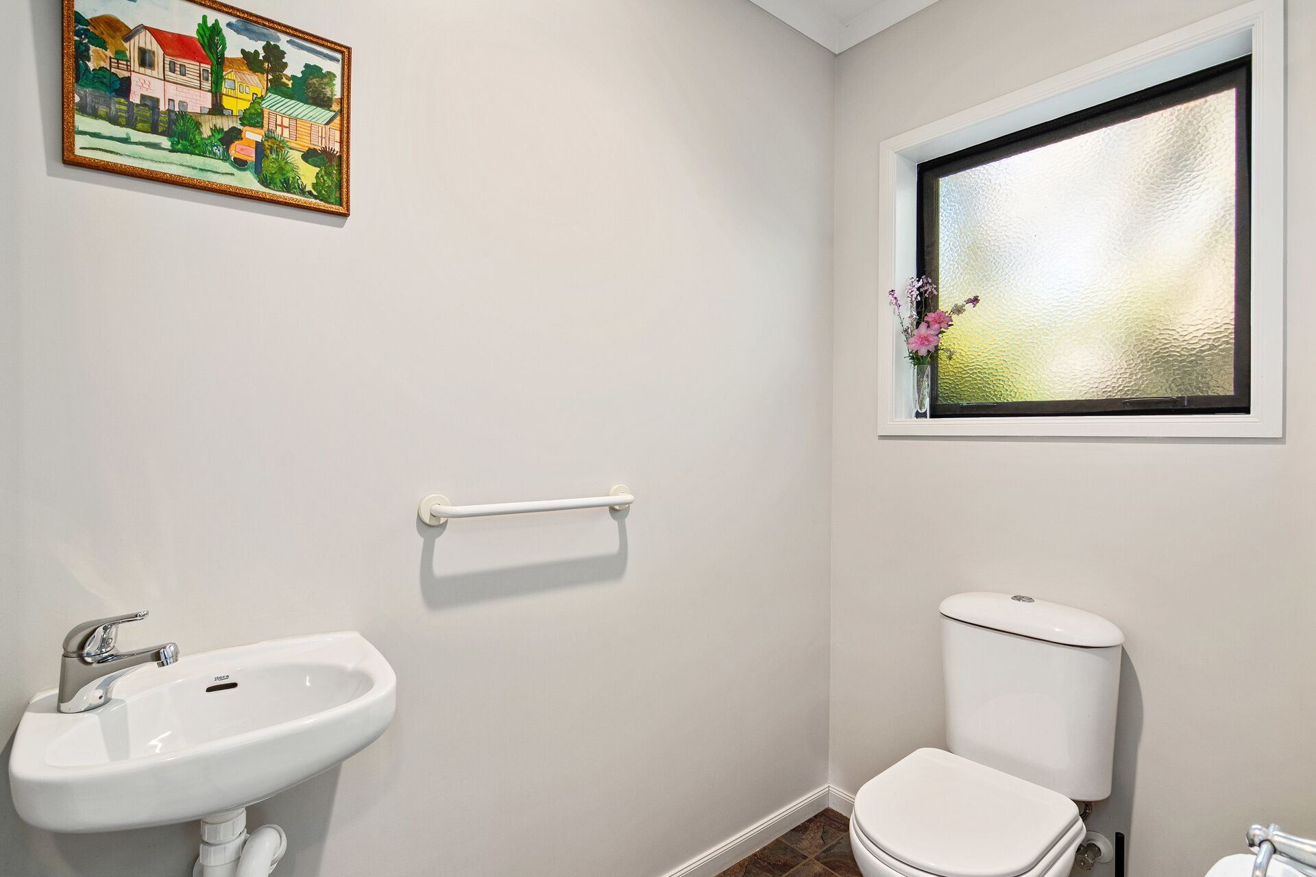 A bathroom with a white sink, a toilet, and a window with frosted glass.