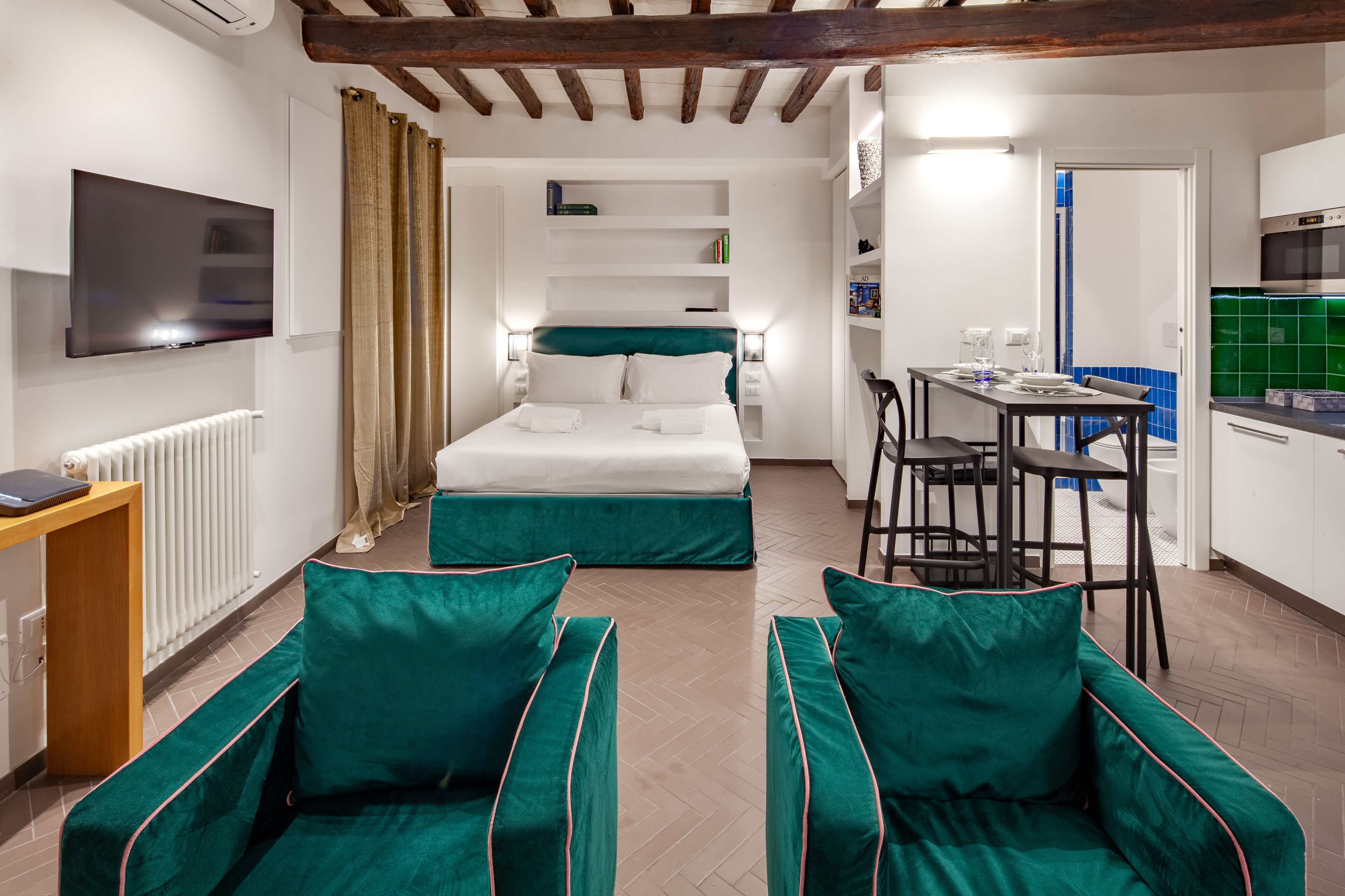 A compact hotel room with a bed, a desk, and a kitchenette.