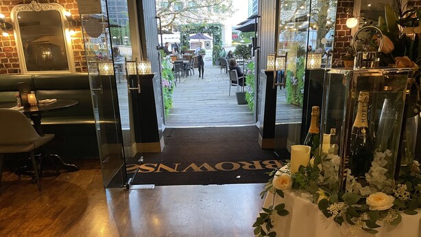 A hotel entrance with a wooden floor, a glass door, and a black mat with "BRONX" written on it. - Stunning View 2 Bed Apartment - Canary Wharf City (London)