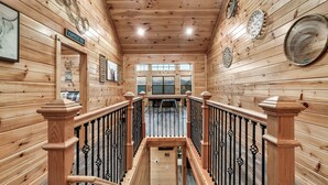 A wooden interior with a staircase, wooden railings, and a sign reading "CATTLE CO". - Family Cabin, 3 King Suites, Game Room, Hot Tub, Minutes to Dollywood (Pigeon Forge)