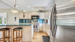Una cucina moderna con elettrodomestici in acciaio inossidabile, mobili in legno e un'isola centrale con sgabelli.