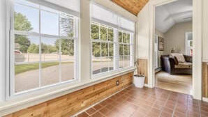 Una stanza con ampie finestre, soffitto in legno e vista su un giardino.