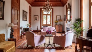 A spacious living room with wooden paneling, a chandelier, and comfortable seating. - Chalet Ficalho (Cascais)