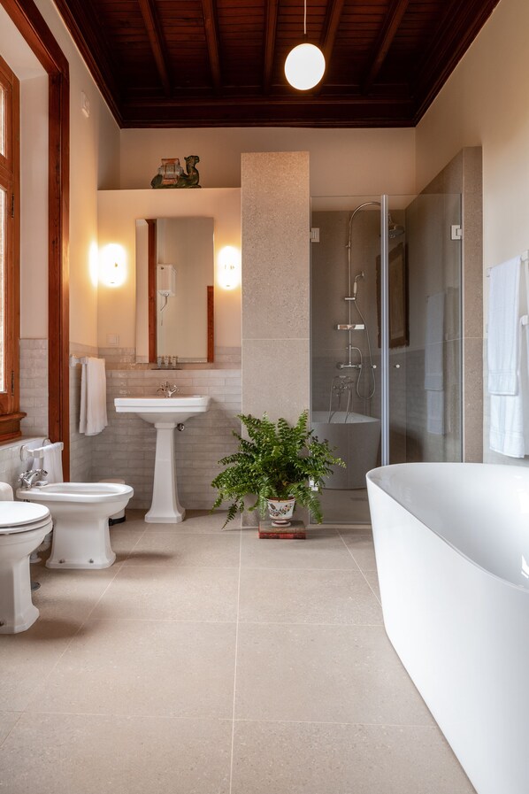 A modern bathroom with a white sink, two toilets, a bathtub, and a glass-enclosed shower. - Chalet Ficalho (Cascais)