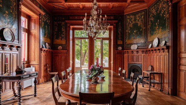 A formal dining room with a large wooden table, chairs, a chandelier, and ornate wall decorations. - Chalet Ficalho (Cascais)