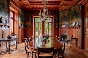 A formal dining room with a large wooden table, chairs, a chandelier, and ornate wall decorations. - Chalet Ficalho (Cascais)