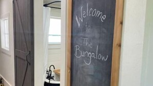 A hallway with a sliding barn door and a chalkboard sign reading "Welcome to The Bungalow".