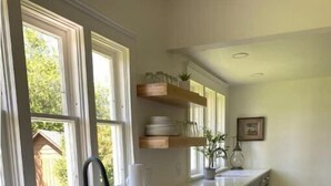 A kitchen with a large window, wooden cabinets, and a countertop.