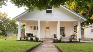 A white house with a covered porch, a front door, and a small window above it.