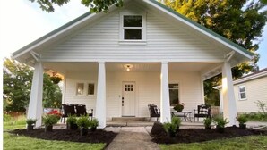 A two-story house with a covered porch, a front door, and a small window above it.