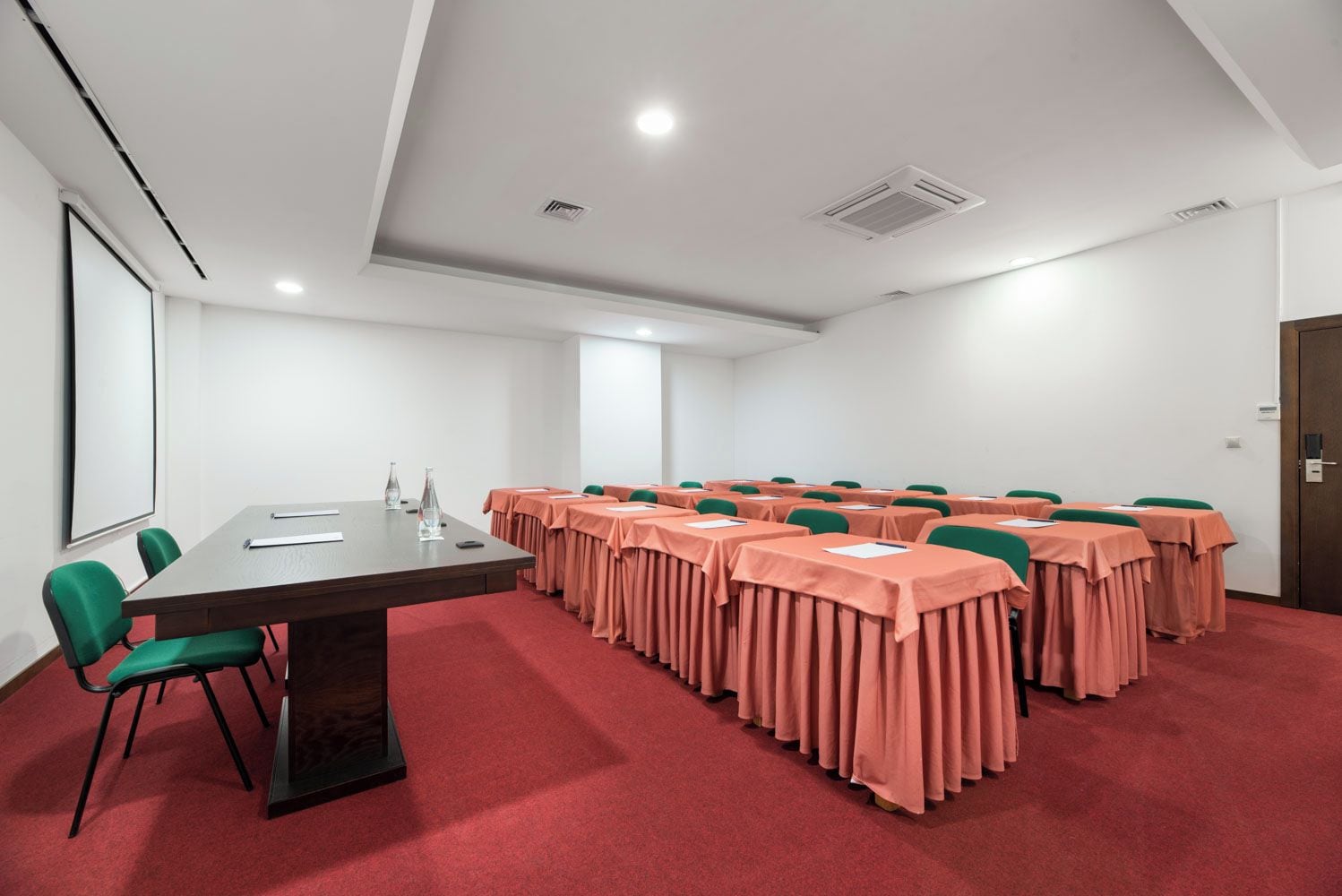 A conference room with a long table, multiple chairs, and a carpeted floor.