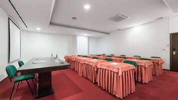 A conference room with a long table, multiple chairs, and a carpeted floor.