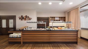 Disposição de buffet com várias estações de serviço, balcão de madeira e exposição de pratos e tigelas fixada na parede.