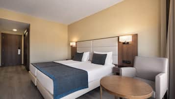Una habitación de hotel con una cama grande, una mesita de noche, una silla y una pequeña mesa.