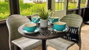 A wicker table set with blue bowls and a potted plant, overlooking a grassy area with a gazebo. - Fishing · Kayaks · Firepit · Paddleboat (Pierceton)