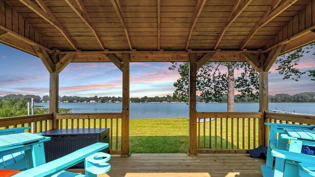 A wooden deck with picnic tables and a view of a lake. - Fishing · Kayaks · Firepit · Paddleboat (Pierceton)