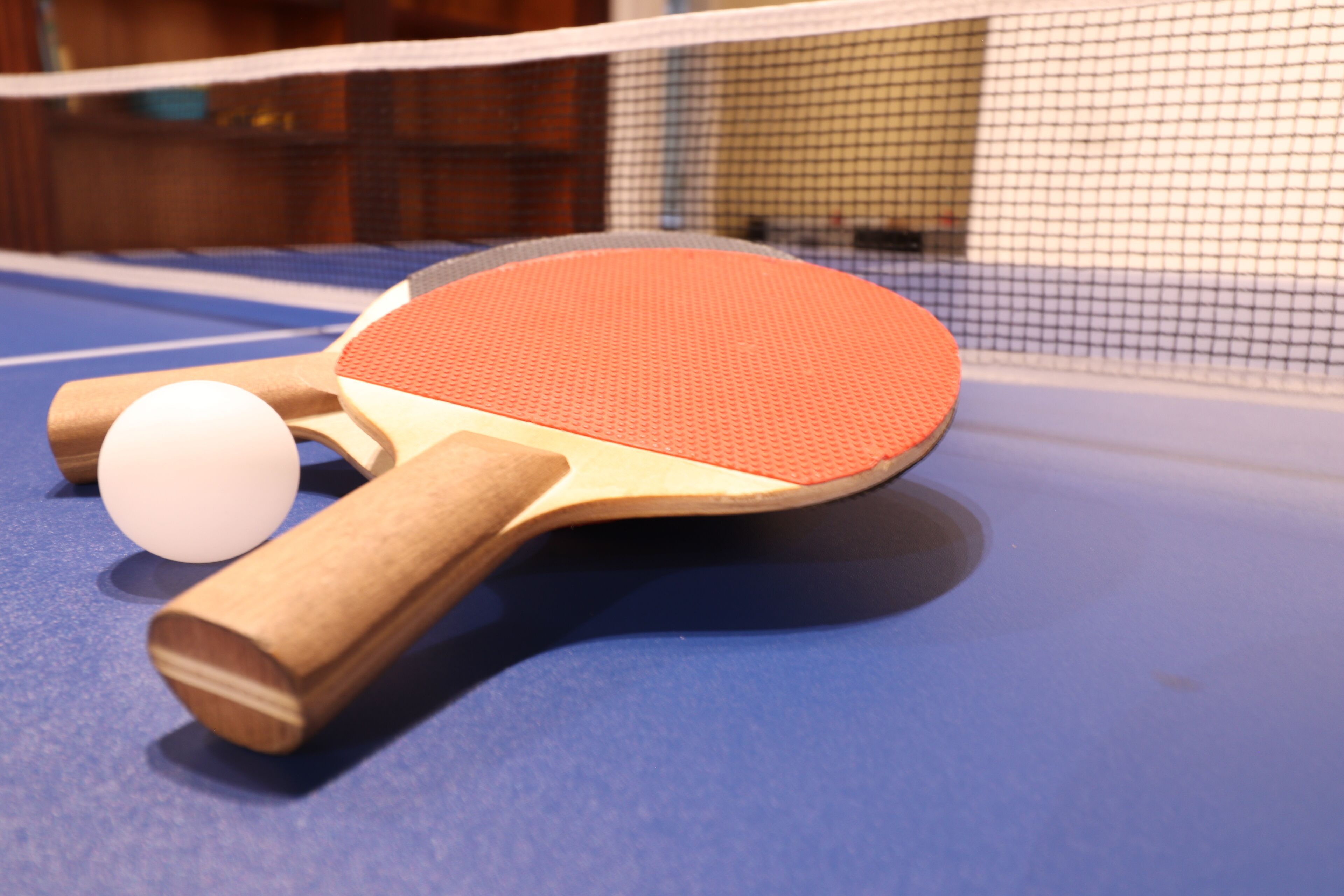 A ping pong table with a paddle and ball.