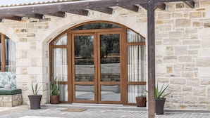 A stone building with a wooden door and potted plants. - Villa Aloe (Pitsidia)