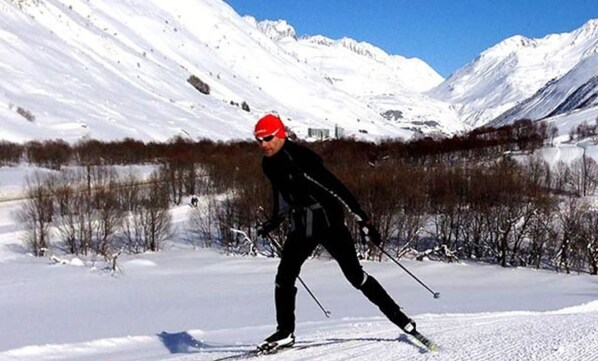 A cross-country skier on a snowy trail with mountains in the background.