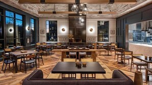 Un restaurante espacioso con techo de madera rústica, ventanas amplias y una zona central con mesas y sillas.
