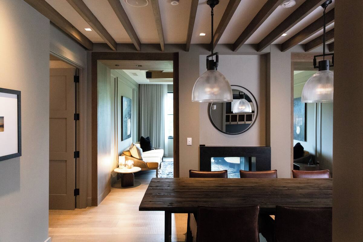 A dining area with a wooden table and chairs, a fireplace, and pendant lights.