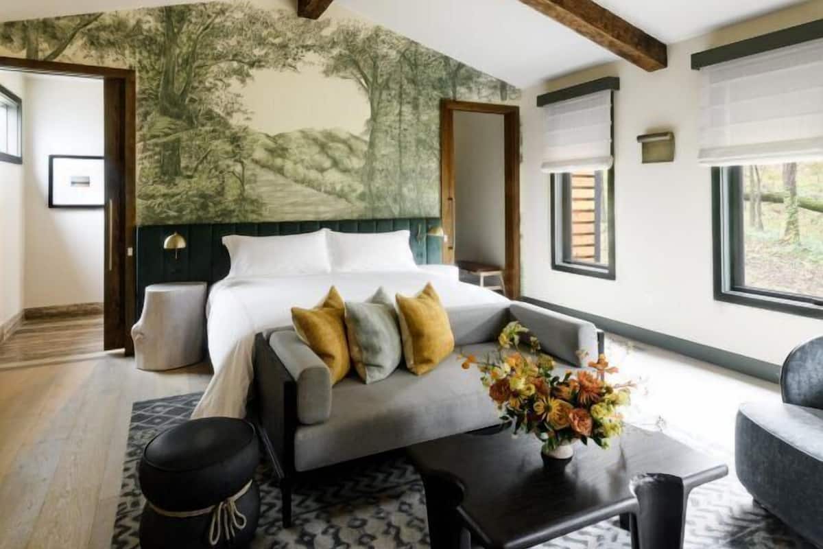 A modern bedroom with a large bed, a sofa, a coffee table, and a ceiling fan.