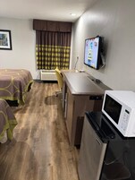 Quarto de hotel com duas camas, uma escrivaninha, micro-ondas e televisão.