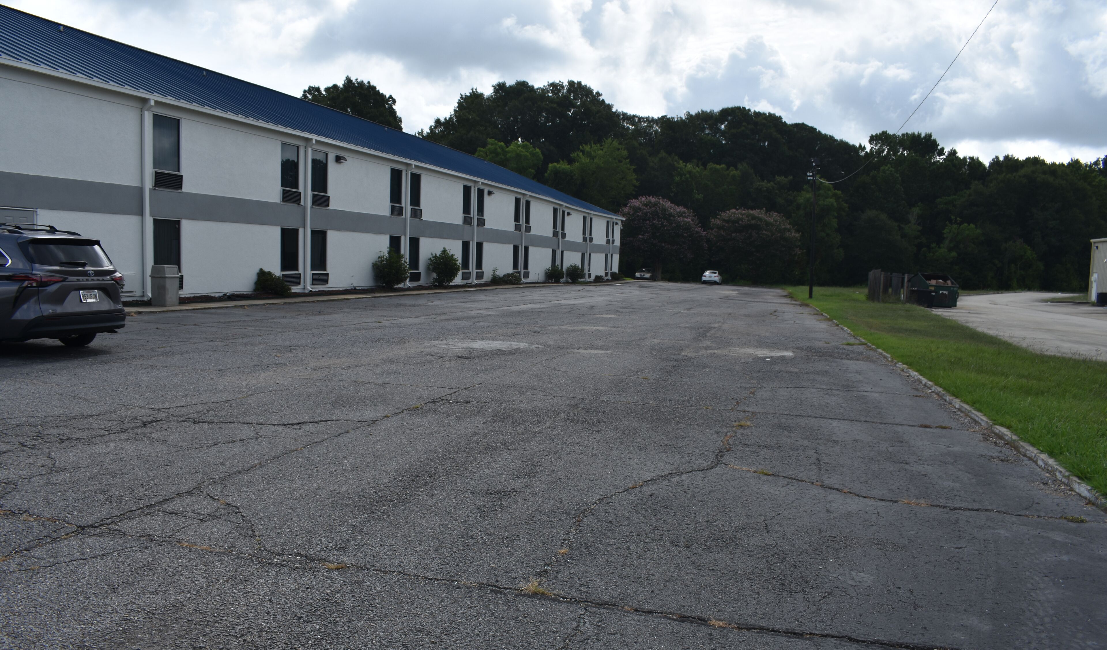A large, multi-story building with a flat roof and a parking lot in front.