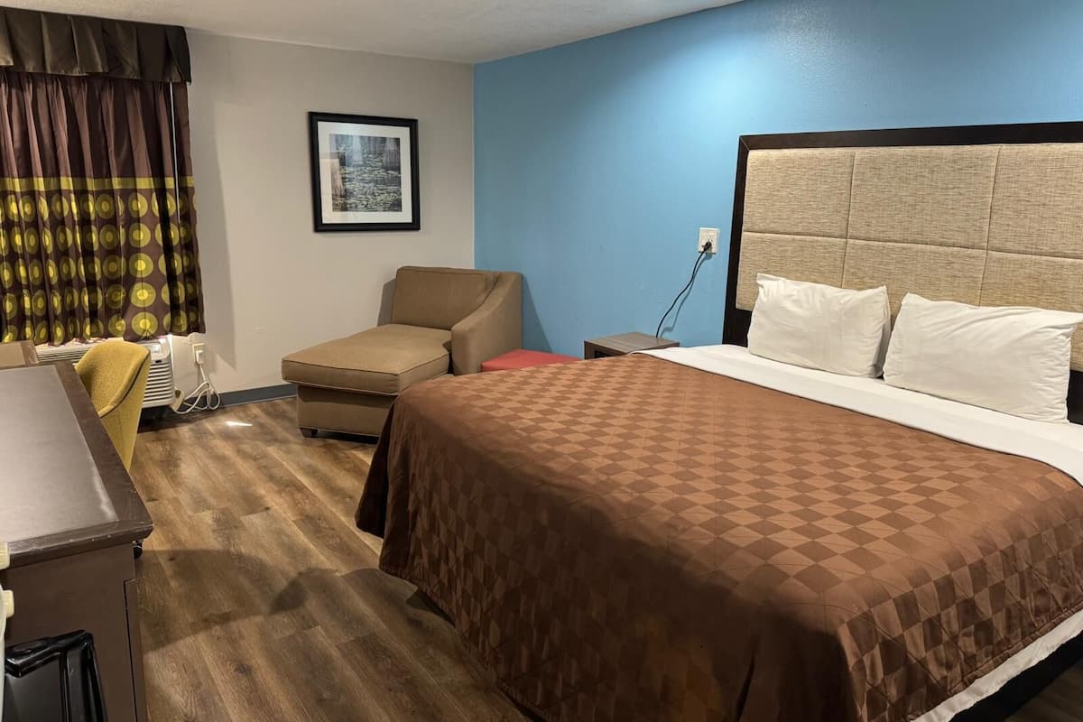 Une chambre d’hôtel avec un lit, un bureau, une chaise et un tableau au mur.