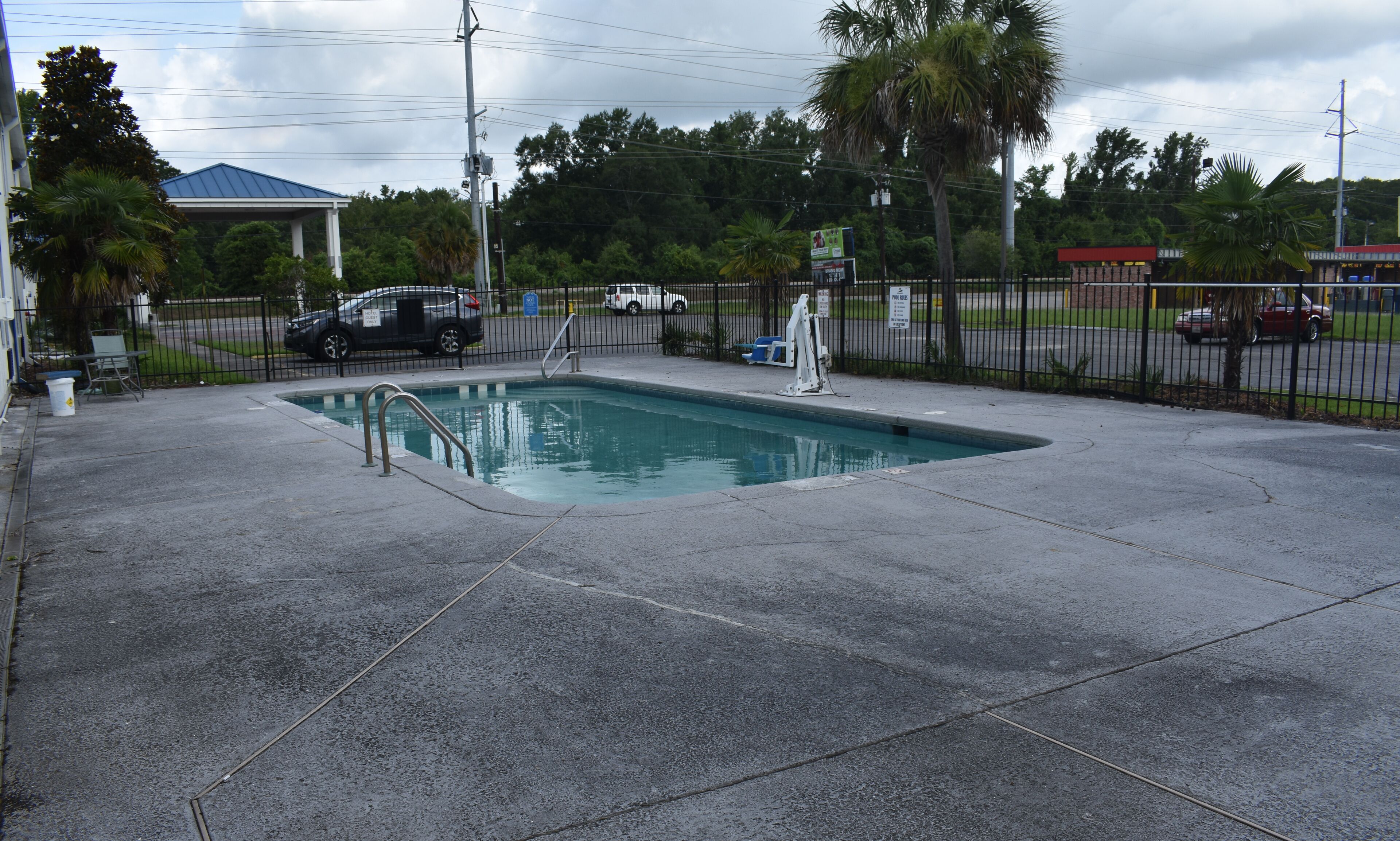 Una piscina rectangular con una escalera de metal, rodeada por una solana de concreto.