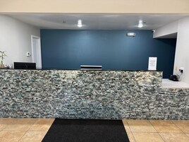 Uma área de recepção com parede azul escura, balcão de azulejos e tapete preto.