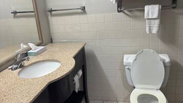 Un baño con lavamanos, espejo, inodoro y toallero.
