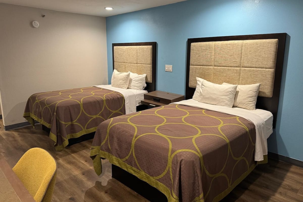 Une chambre d’hôtel avec deux lits, chacun doté d’une tête de lit et recouvert d’une couverture marron ornée de cercles jaunes.