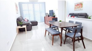 Una sala de estar moderna con una mesa de comedor, un sofá gris y un televisor sobre un mueble.