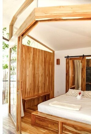 Une chambre à coucher avec un cadre en bois, comprenant un grand lit, un banc et une porte coulissante.