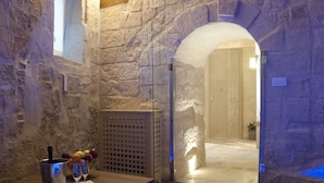 A stone-walled room with a hot tub, a wooden door, and a small window. - MATA SUITE (Matera)