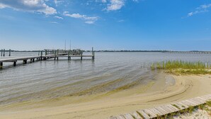 Un muelle de madera se extiende sobre aguas tranquilas bajo un cielo despejado.