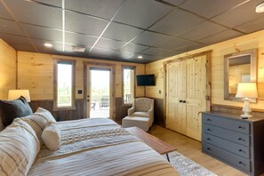 A bedroom with a bed, dresser, chair, TV, and wooden walls. - Blue Ridge Vacation Rental w/ Deck & Game Room! (Blue Ridge)