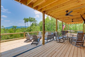 A wooden deck with outdoor furniture and a view of a forest and mountains. - Blue Ridge Vacation Rental w/ Deck & Game Room! (Blue Ridge)