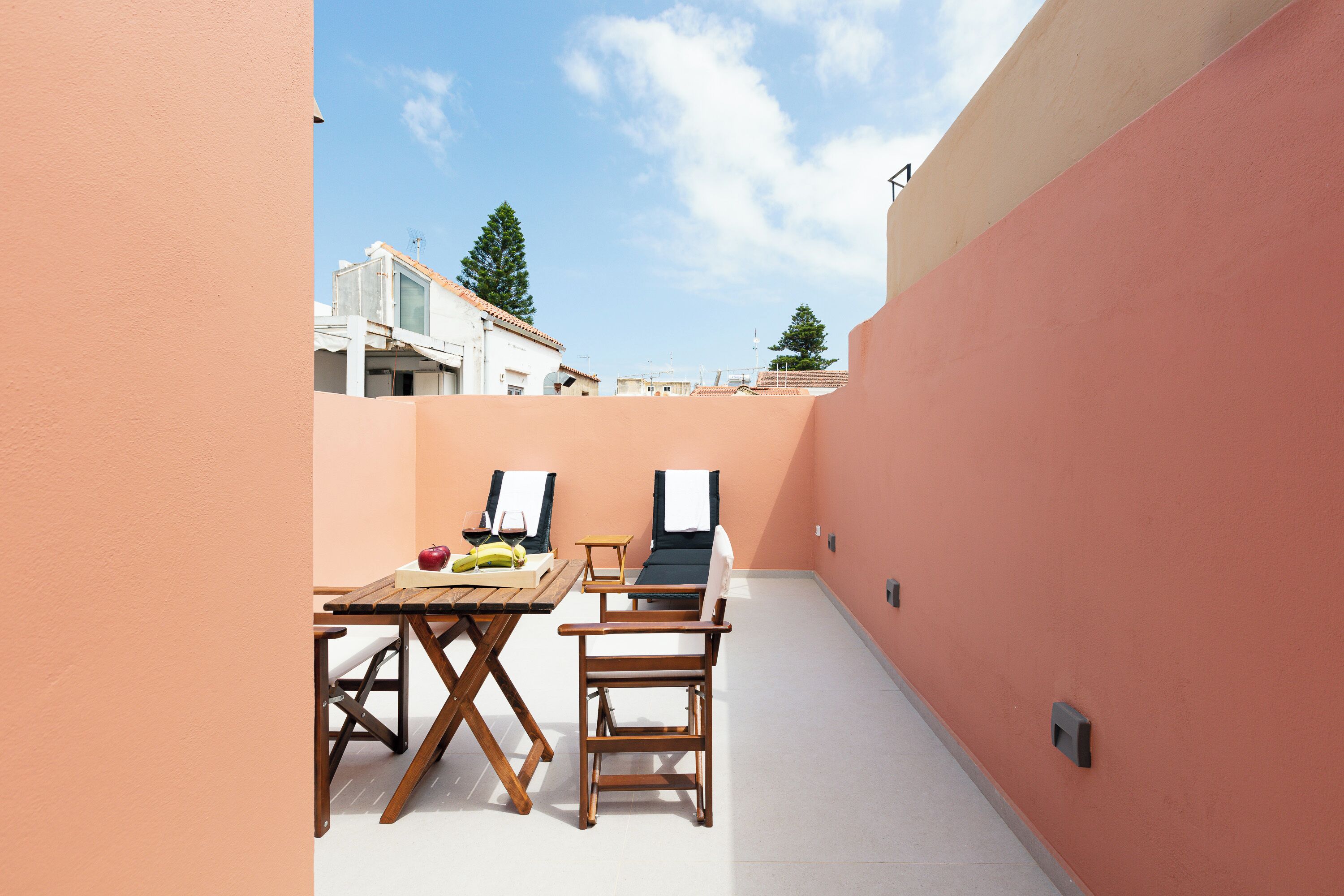 A patio with a table, chairs, and a sun lounger.