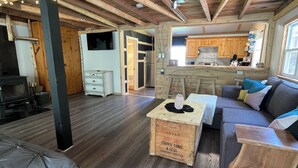 A spacious living area with a wooden floor, a sofa, a coffee table, and string lights on the ceiling.