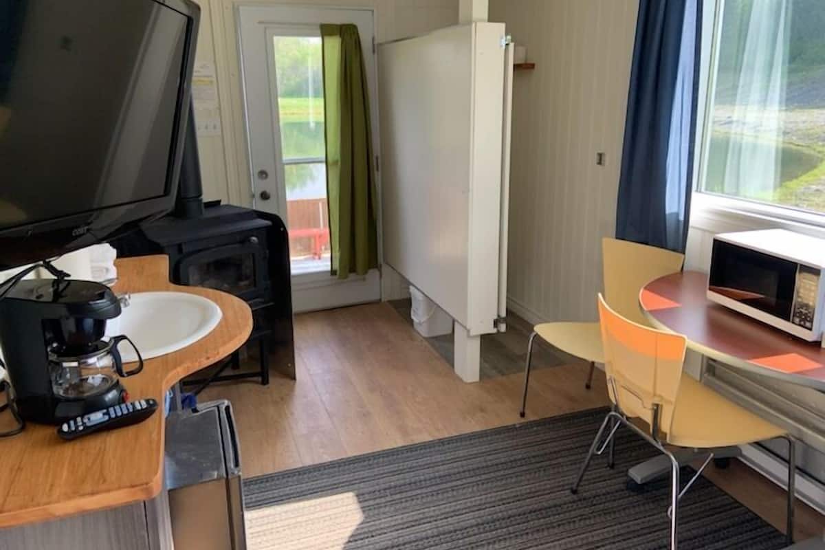 Una habitación compacta con televisión, cafetera, microondas, una pequeña mesa y una silla.