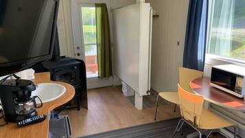 Una habitación compacta con televisión, cafetera, microondas, una pequeña mesa y una silla.