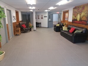 Eine geräumige Lobby mit einer Rezeption, Ledersofas und einem großen Gemälde an der Wand.