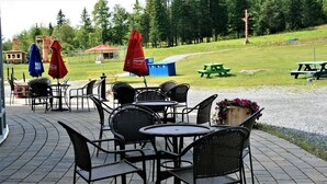 Outdoor seating with tables and chairs, umbrellas, and a picnic table. - Parc du Mont-Citadelle (Saint-Honoré-de-Témiscouata)