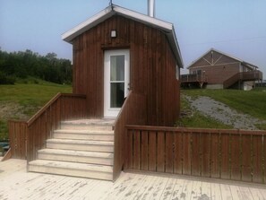 Eine Holzhütte mit einer kleinen Veranda und Stufen, die zu einer Tür führen.