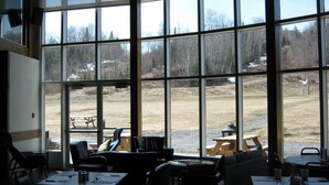 A room with large windows, tables, and chairs arranged for dining or meetings. - Parc du Mont-Citadelle (Saint-Honoré-de-Témiscouata)