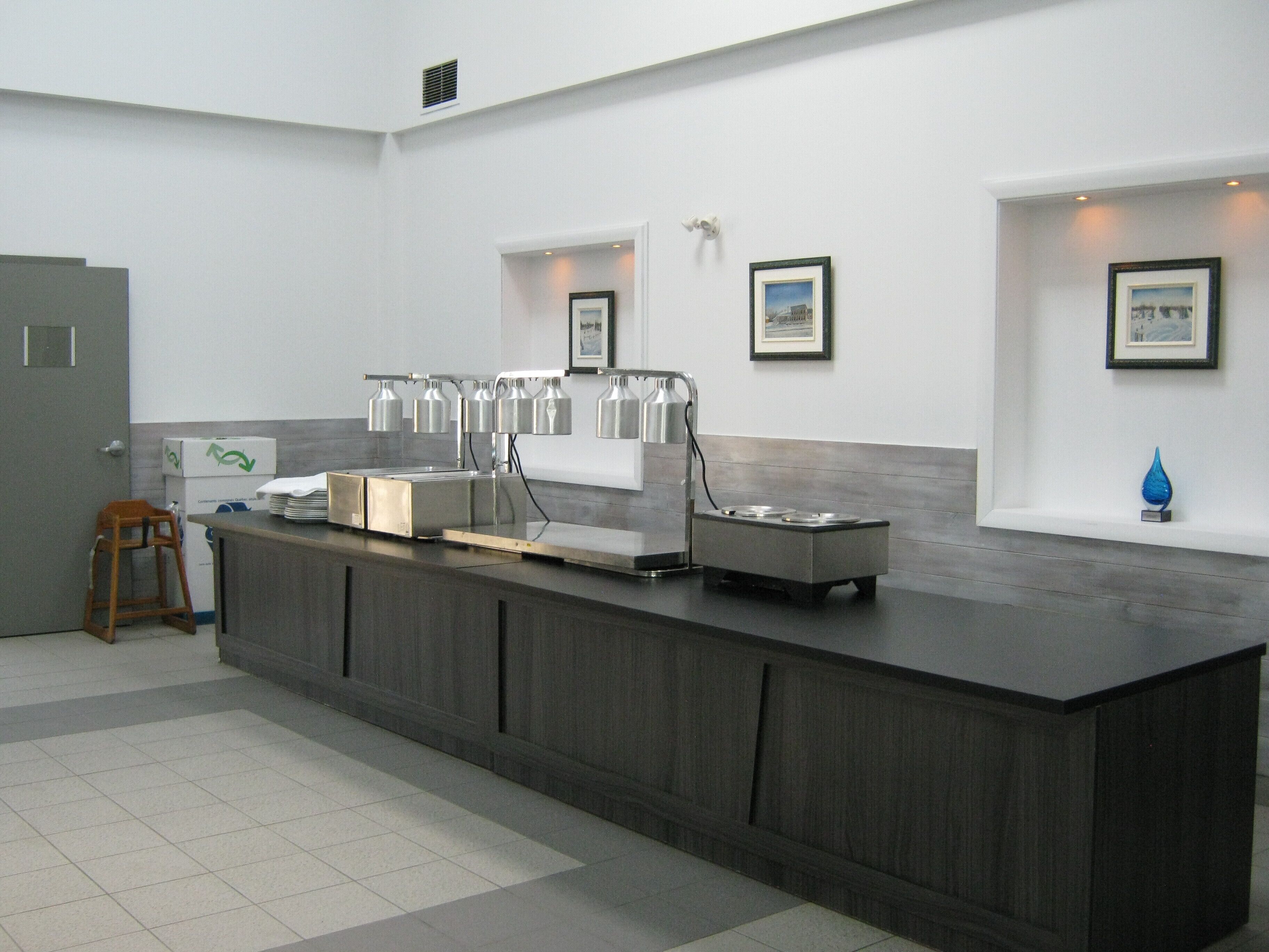 A modern kitchen with a long counter, a coffee station, and framed pictures on the walls.