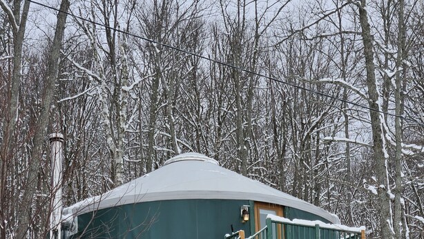 A snow-covered yurt with a wooden staircase leading to a platform. - Parc du Mont-Citadelle (Saint-Honoré-de-Témiscouata)