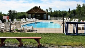 A swimming pool area with lounge chairs, a small building, and a fenced enclosure. - Parc du Mont-Citadelle (Saint-Honoré-de-Témiscouata)